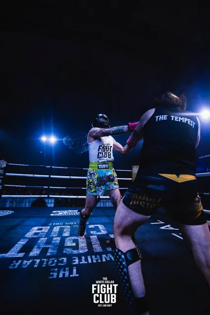 Alex in the ring from behind, his black top printed with 'The Tempest', throwing a punch.